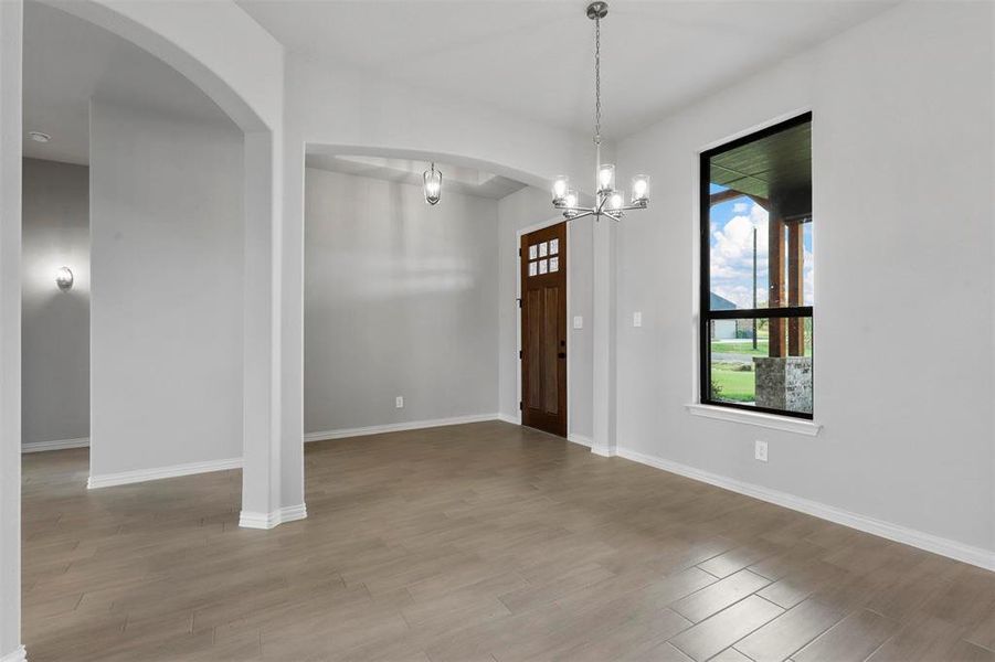 Unfurnished dining area featuring an inviting chandelier and hardwood / wood-style floors