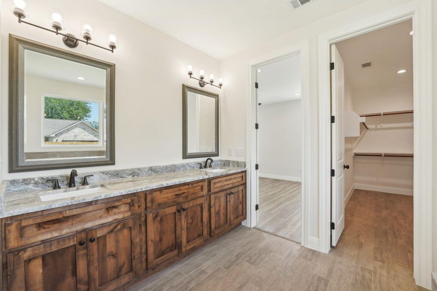 Bathroom with double vanity, wood tile floors, a spacious closet, and a sink Bathroom with double vanity, wood tile floors, a spacious closet, and a sink