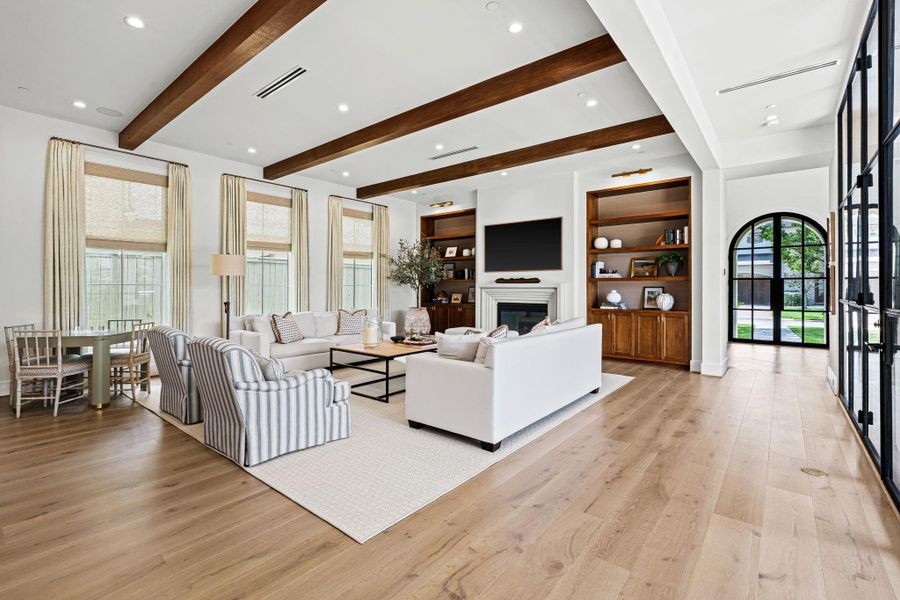 The spacious light-filled family room is anchored by a cast stone gas-log fireplace, creating a warm focal point. Custom Rift-Sawn white oak built-ins w/ Philip Jeffries grass cloth backing add both texture & functionality, while wood beam ceiling details introduce architectural depth. Designed to accommodate large-scale furnishings, ideal for both everyday living & entertaining. The spacious light-filled family room is anchored by a cast stone gas-log fireplace, creating a warm focal point. Custom Rift-Sawn white oak built-ins w/ Philip Jeffries grass cloth backing add both texture & functionality, while wood beam ceiling details introduce architectural depth. Designed to accommodate large-scale furnishings, ideal for both everyday living & entertaining.
