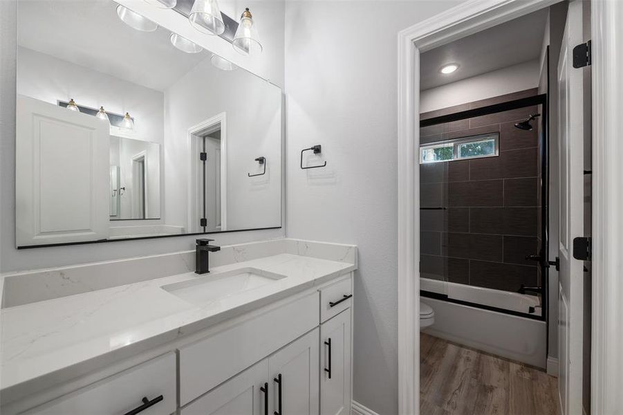 Full bath with vanity, wood finished floors, and shower / bath combination Full bath with vanity, wood finished floors, and shower / bath combination