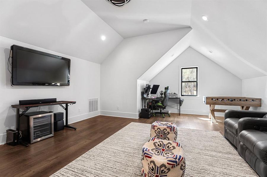 Living area with vaulted ceiling, wood finished floors, baseboards, visible vents, and recessed lighting Living area with vaulted ceiling, wood finished floors, baseboards, visible vents, and recessed lighting