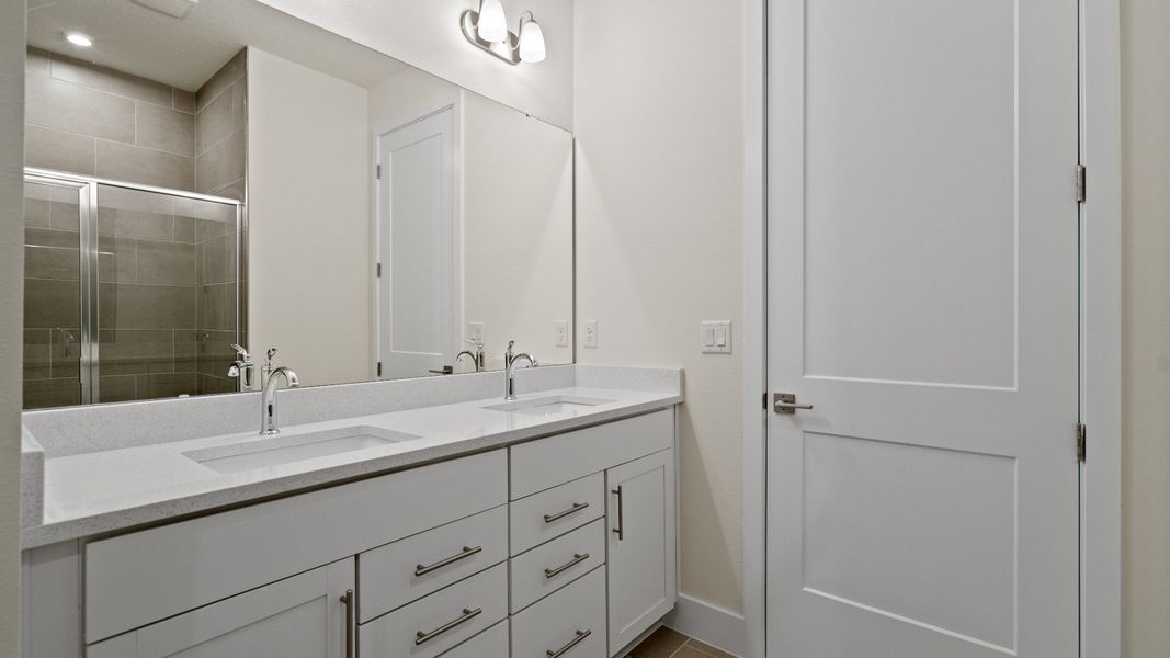 Primary En Suite Bath with Dual Sinks and Walk-In Glass Encased Shower in the Longleaf by DRB Homes New Home in Saint Cloud