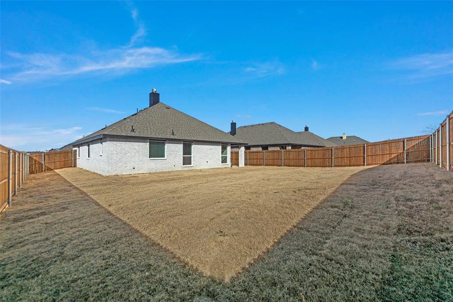 Back of property featuring a chimney, a fenced backyard, and brick siding