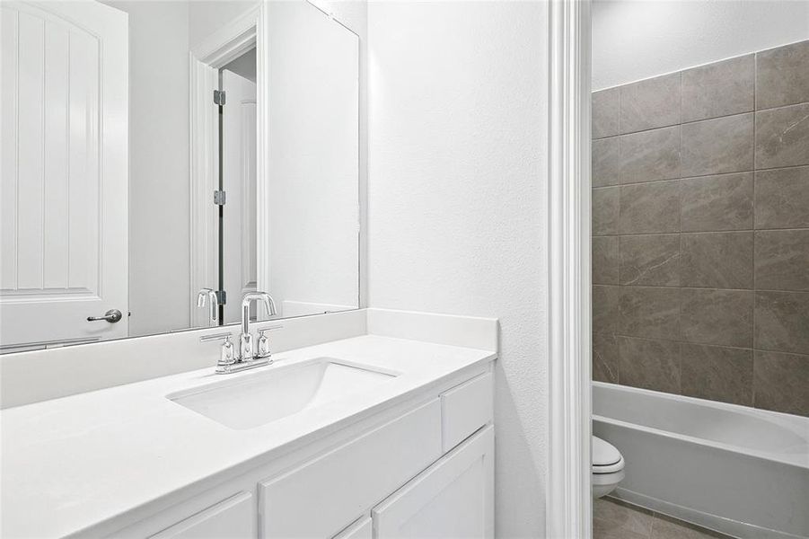 Bathroom with vanity, bathing tub / shower combination, and a textured wall