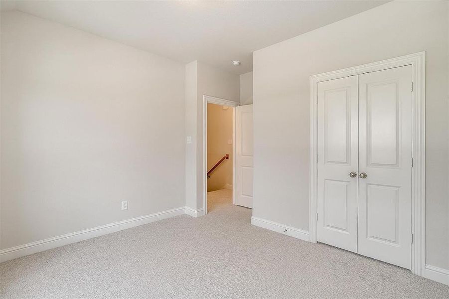 Unfurnished bedroom featuring light carpet and a closet