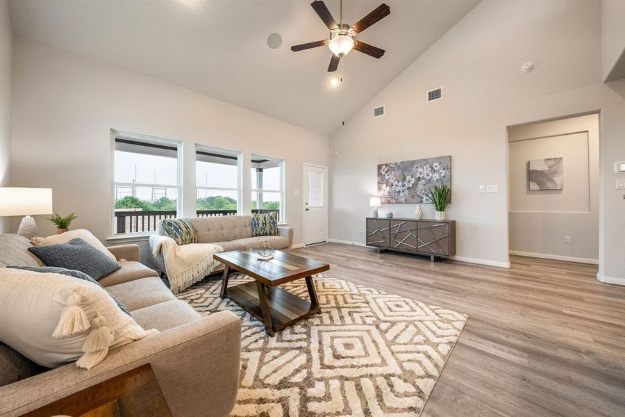 Relax and unwind in this inviting family room, illuminated by abundant natural light streaming in through tall windows, complemented by high ceilings and stunning flooring. Stay comfortable year-round with the gentle breeze from the ceiling fan, creating the perfect atmosphere for family gatherings. Sample photo of completed home. Actual color and selections may vary.