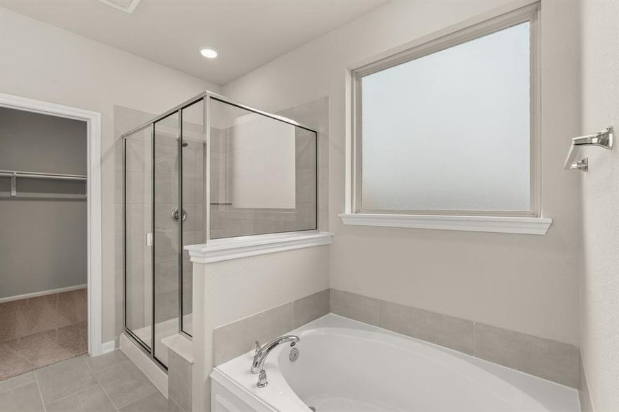 This additional view of your primary bathroom features tile flooring, fresh paint, walk-in shower, a separate garden tub, and a large walk-in closet.