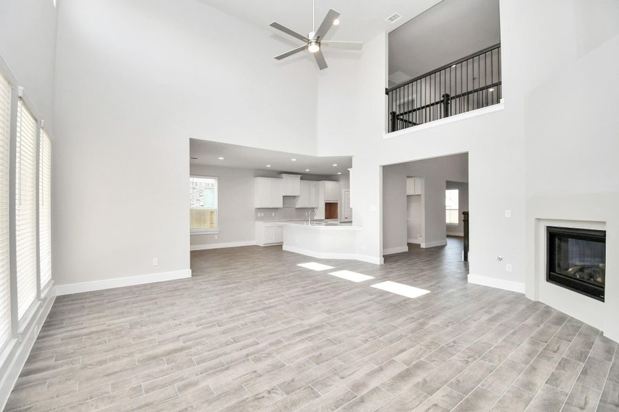 Family room flooded with natural light through the expansive windows.  The premium tile flooring adds a touch of luxury to the space, creating the perfect setting for relaxing moments and cherished gatherings with loved ones. Sample photo of completed home with similar floor plan. Actual colors and selections may vary.