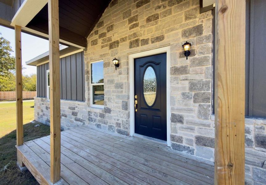 Doorway to property with stone siding, a porch, and board and batten siding Doorway to property with stone siding, a porch, and board and batten siding
