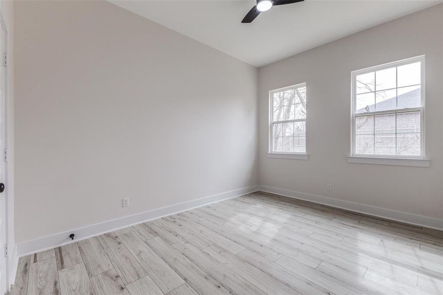 Spare room with light wood finished floors, ceiling fan, and baseboards