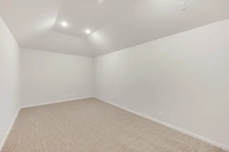 Empty bedroom with vaulted ceiling, recessed lighting, and beige carpet