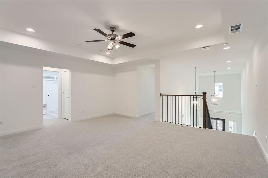 Empty room with light colored carpet and ceiling fan