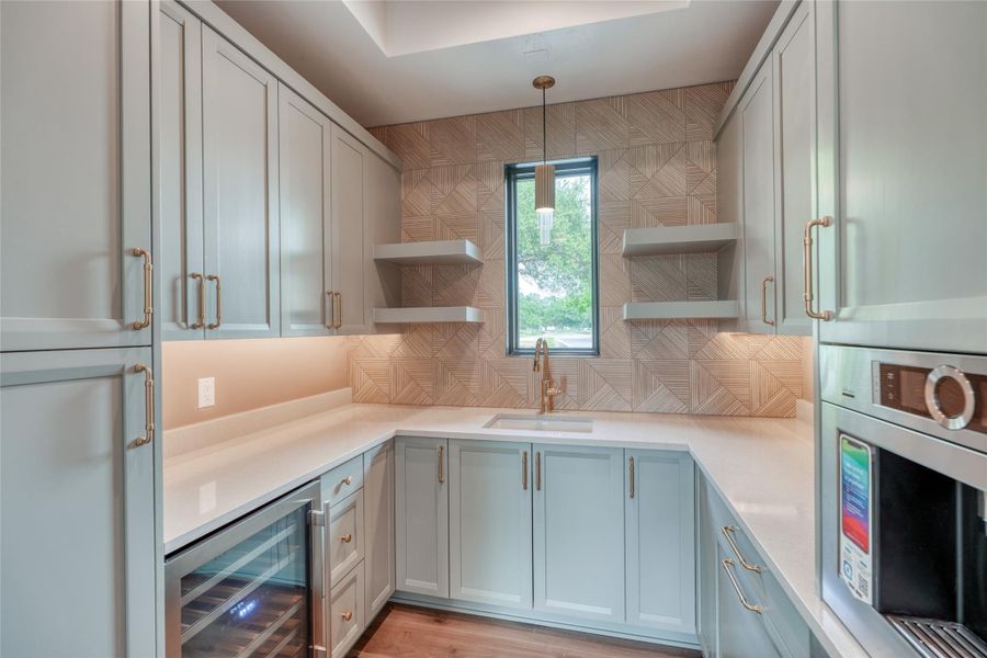 Kitchen featuring wine cooler, open shelves, a sink, stainless steel oven, and decorative backsplash