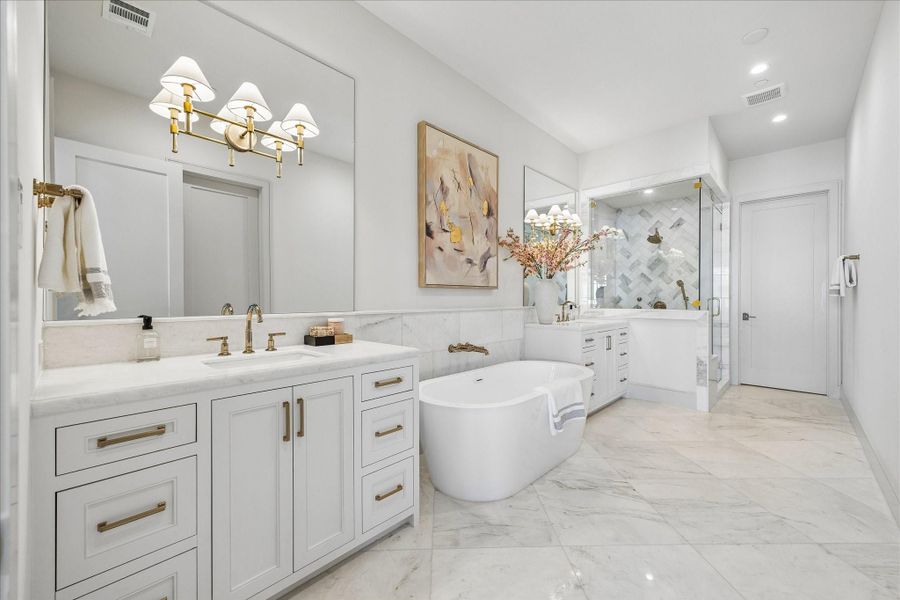 Kalta Bianco polished marble makes the primary bathroom gleam. 24x24 tile flooring, large format brick design wainscoting, and herringbone shower accent wall keep the visual interest while tying together the look. The 67" Mermaid free-stading tub will be a joy to soak in. All the bathrooms feature the same on-site built, recessed panel cabinetry found in the kitchen.