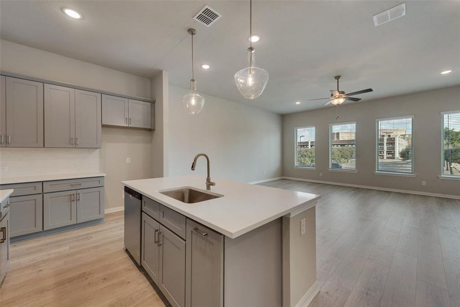 Kitchen with sink, light hardwood / wood-style flooring, plenty of natural light, and a kitchen island with sink