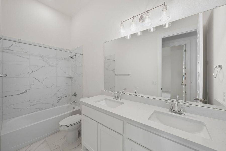 Full bath featuring shower / washtub combination, double vanity, and light marble finish floors Full bath featuring shower / washtub combination, double vanity, and light marble finish floors