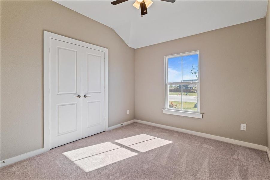 bedroom featuring a closet, light colored carpet, ceiling fan, and lofted ceiling