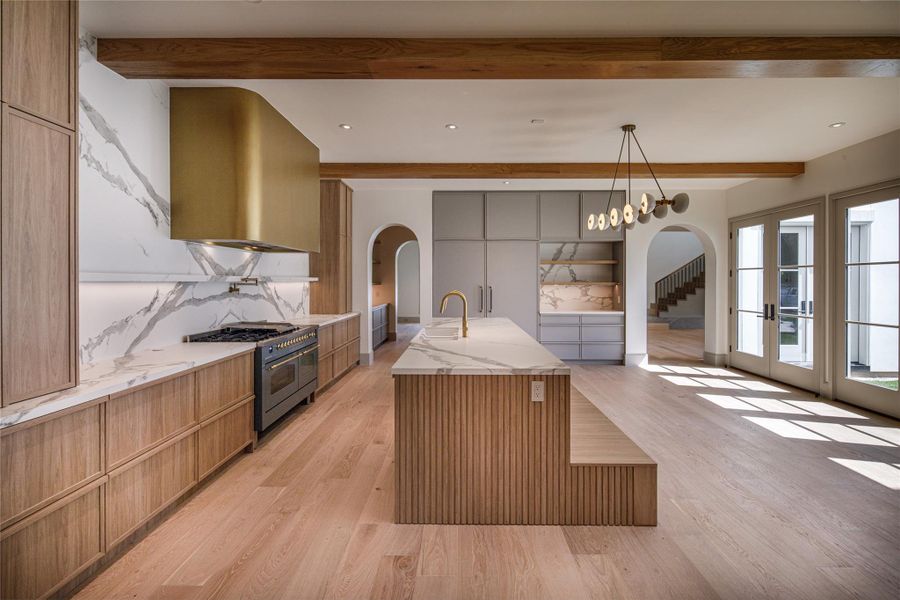 Every angle was considered. The oversized island anchors the kitchen while French doors bring sunlight in from the private courtyard, and arched openings keep the newly completed floor plan connected without making it feel completely open.