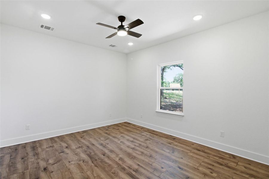 A well-lit bedroom with modern wood-look flooring and a functional ceiling fan for comfort. A well-lit bedroom with modern wood-look flooring and a functional ceiling fan for comfort.
