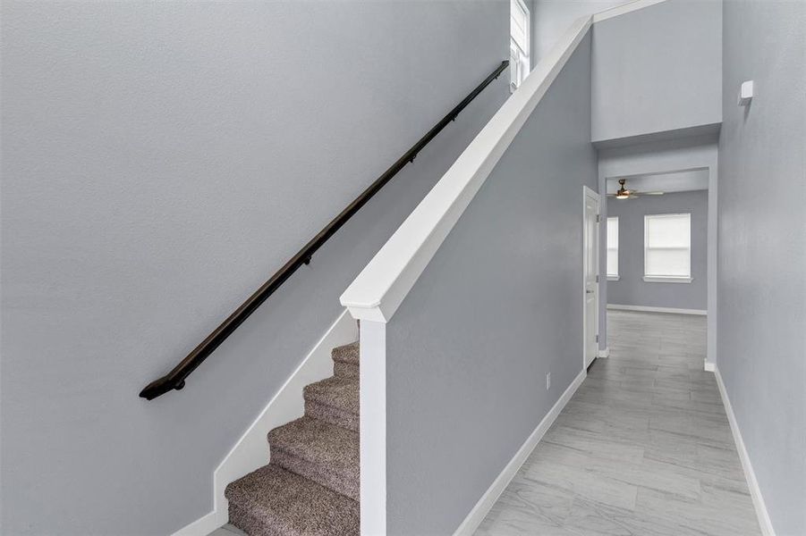 Stairway featuring a ceiling fan and a high ceiling