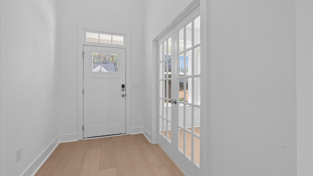 Highly functional foyer with hardwood flooring that flows seamlessly into living spaces