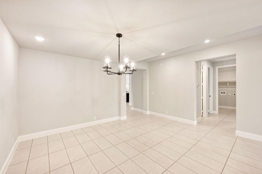 Empty dining room with light tile floors, black chandelier, and open doorway to hallway Empty dining room with light tile floors, black chandelier, and open doorway to hallway