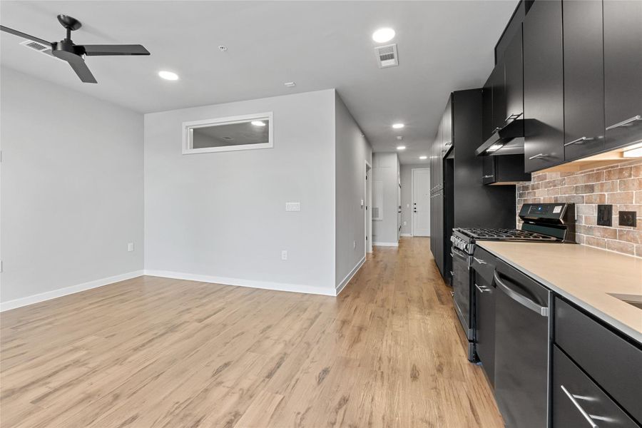 Kitchen featuring appliances with stainless steel finishes, dark cabinetry, ceiling fan, backsplash, and light wood-type flooring