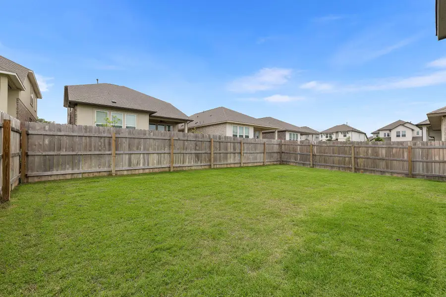 Spacious backyard featuring a manicured lawn, full wood fencing, and ample open area