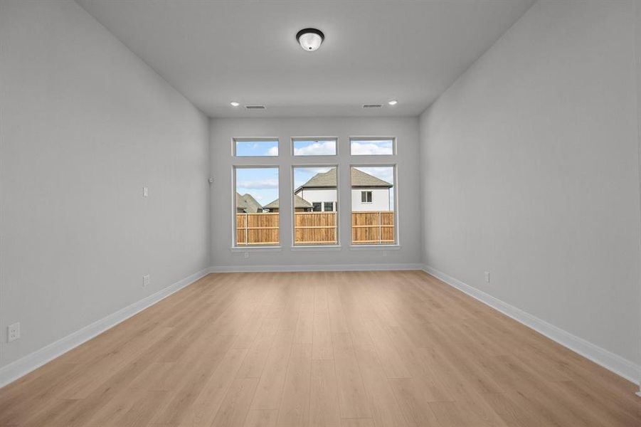 Spacious room featuring light wood-finish flooring, white baseboards, and a neutral wall color Spacious room featuring light wood-finish flooring, white baseboards, and a neutral wall color