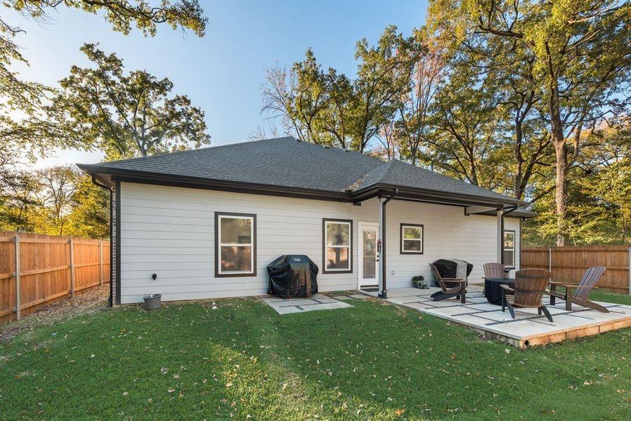 Rear view of house with a fenced backyard, a patio, and roof with shingles