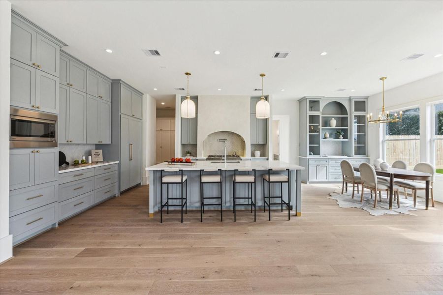 Designer kitchen with custom cabinetry, a large island, premium appliances, and stylish lighting that anchors the space.