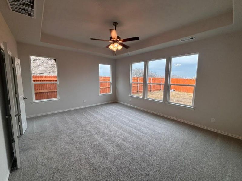 Spare room with a tray ceiling, carpet flooring, and ceiling fan Spare room with a tray ceiling, carpet flooring, and ceiling fan