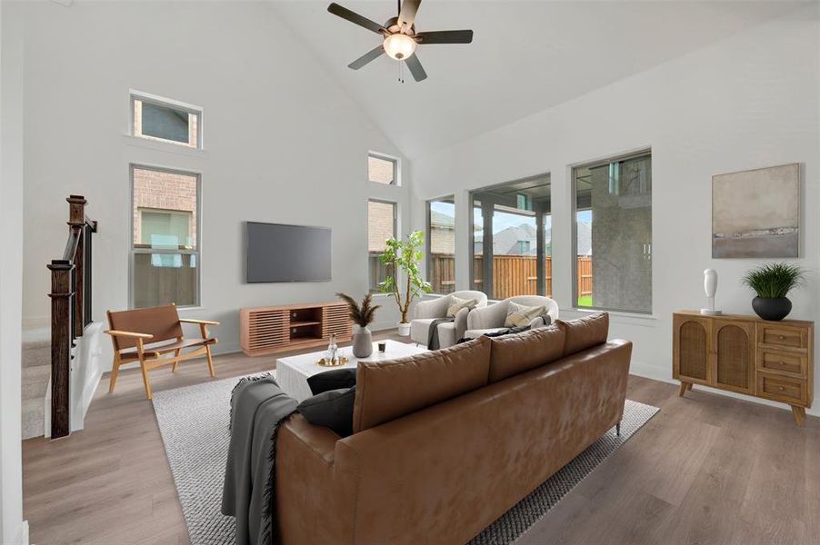 Living area featuring high vaulted ceilings with a ceiling fan, wood-finish flooring, and multiple large windows