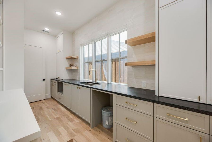 The butler's pantry serves as a sophisticated transition space between the dining room and the kitchen, designed for both high-end entertaining and practical storage.