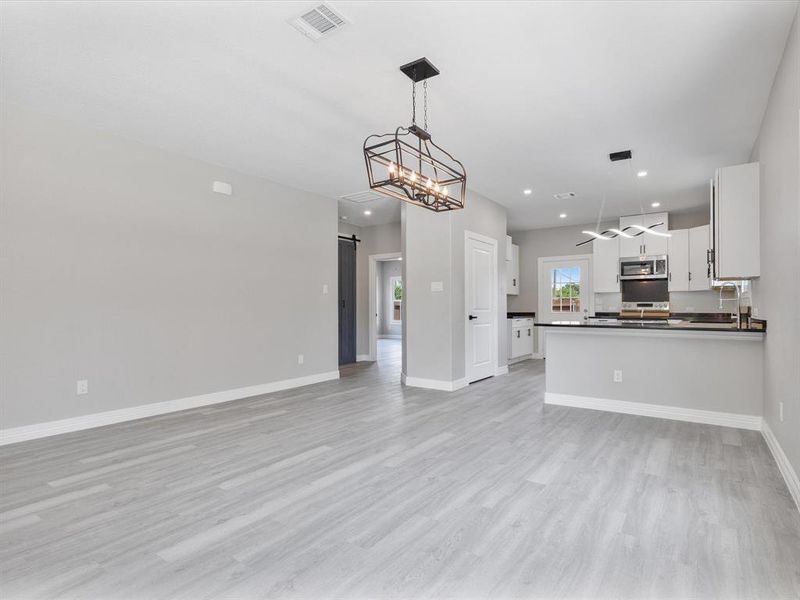 Kitchen with stainless steel appliances, a barn door, dark countertops, open floor plan, and recessed lighting