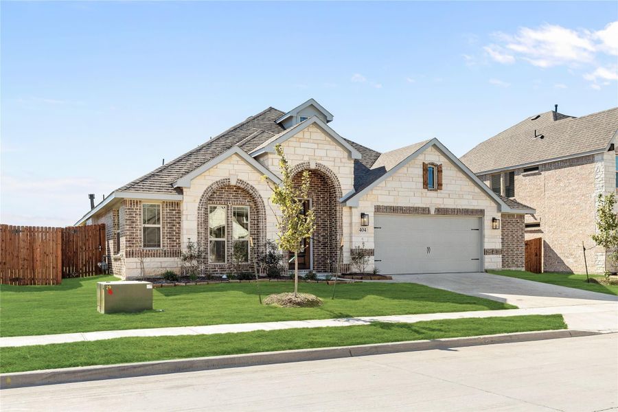 Single-story home with brick and stone exterior, arched entryway, two-car garage, and green front lawn.
