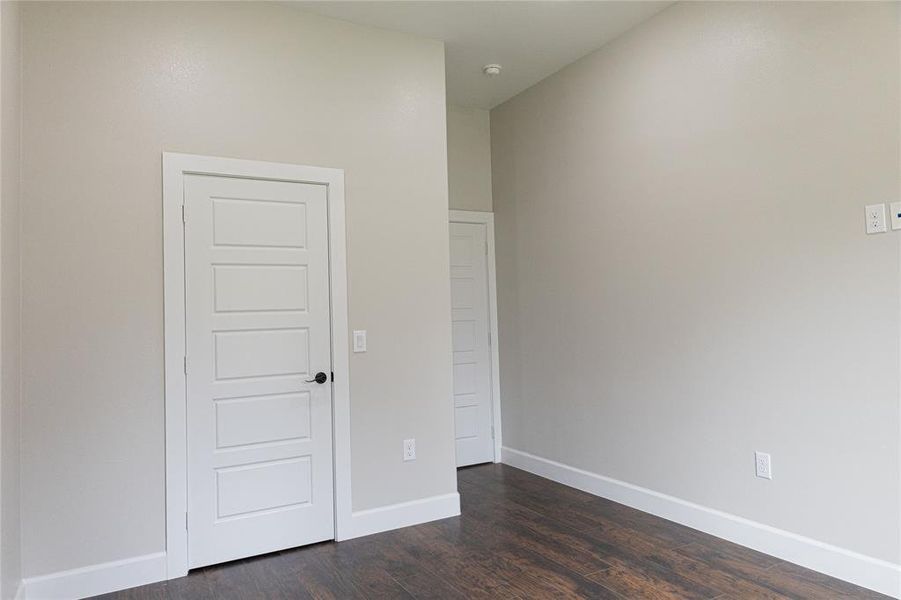 Unfurnished room with dark wood-type flooring and baseboards Unfurnished room with dark wood-type flooring and baseboards