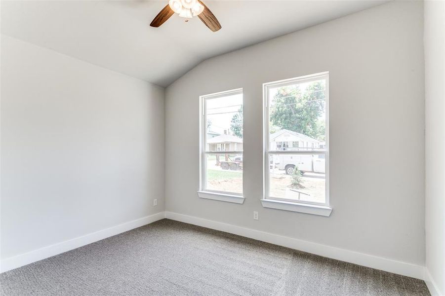 Carpeted spare room featuring lofted ceiling and ceiling fan