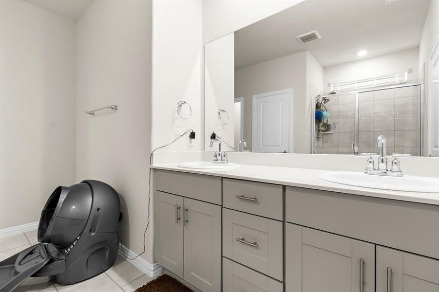 Bathroom with double vanity, tile patterned floors, and a stall shower Bathroom with double vanity, tile patterned floors, and a stall shower