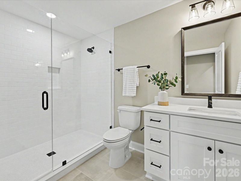 Modern third full bath on upper level features a sleek glass-enclosed tile shower, contemporary fixtures, and stylish finishes throughout.
