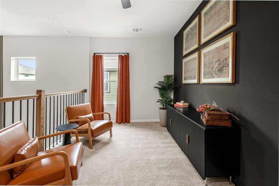 Living area with light colored carpet and a ceiling fan