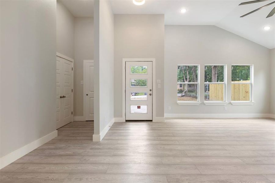 Foyer with light hardwood / wood-style floors, a wealth of natural light, high vaulted ceiling, and ceiling fan