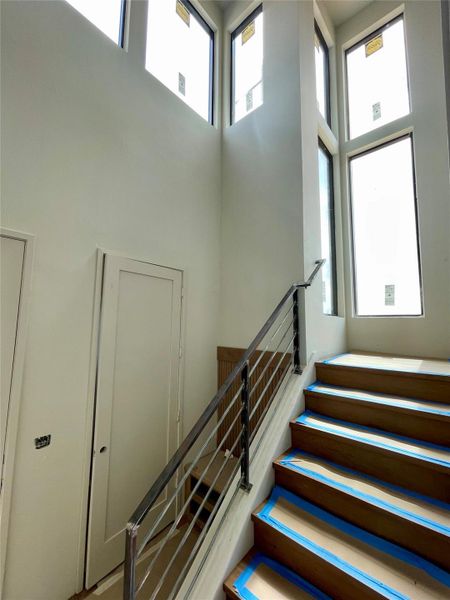 Staircase featuring dark wood steps, a modern metal railing, and high windows providing natural light