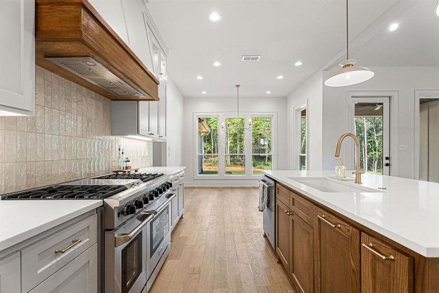 Kitchen with appliances with stainless steel finishes, healthy amount of natural light, light wood-style flooring, pendant lighting, and recessed lighting
