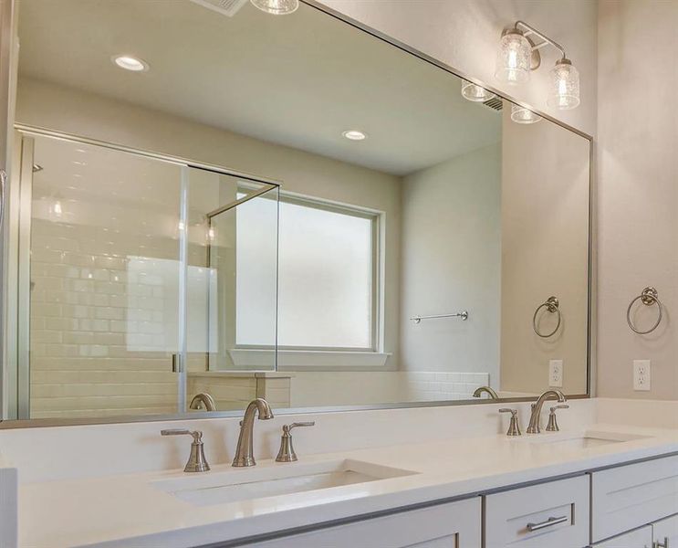 Bathroom featuring double vanity, recessed lighting, and an enclosed shower
