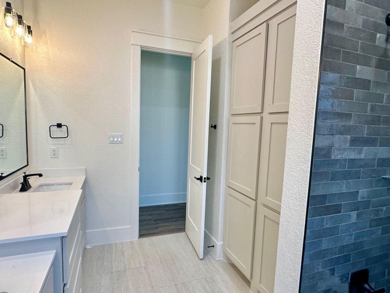Full bathroom with double vanity and a textured wall