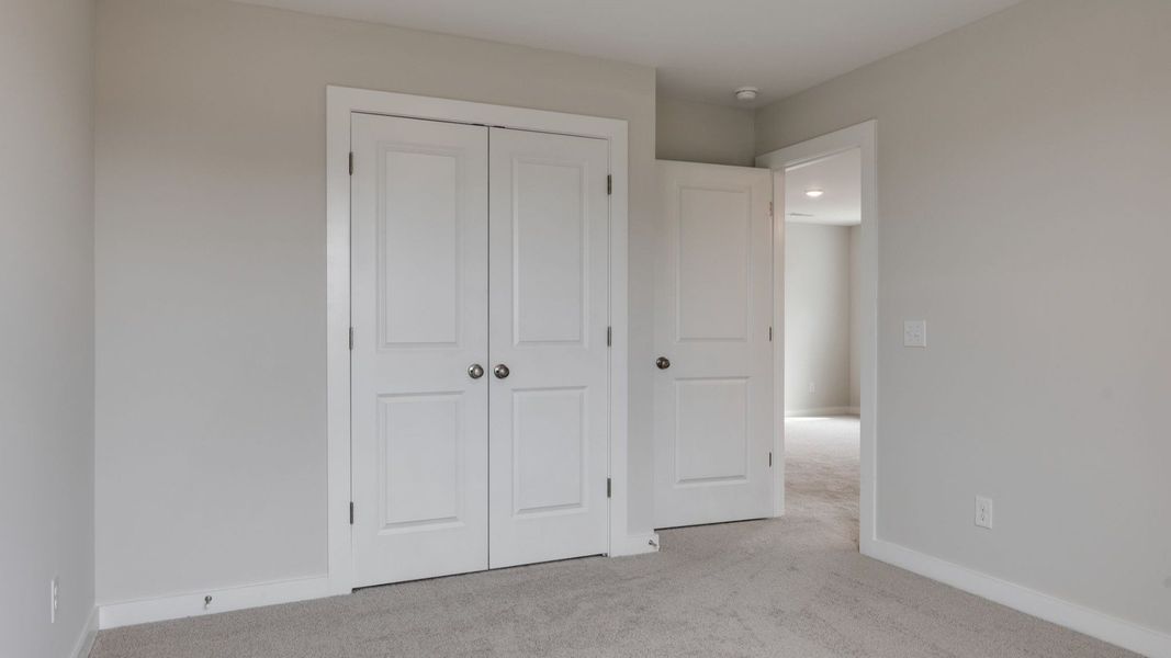 Secondary bedroom with window and double door closet