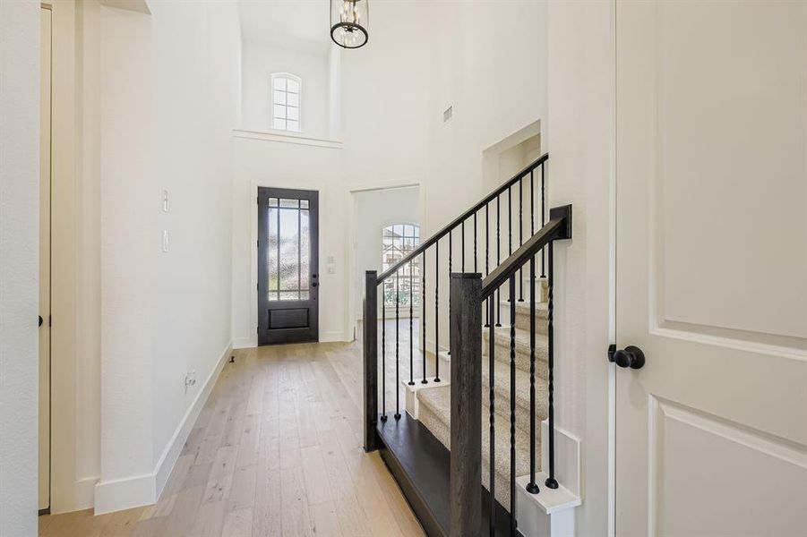 Foyer featuring light wood-style floors, stairs, and a towering ceiling Foyer featuring light wood-style floors, stairs, and a towering ceiling