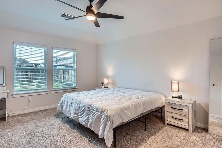 Bedroom featuring visible vents, light colored carpet, and baseboards