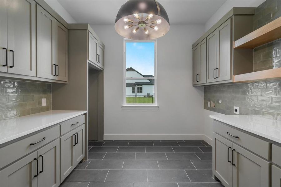 Washroom with hookup for an electric dryer, dark tile patterned floors, and cabinets